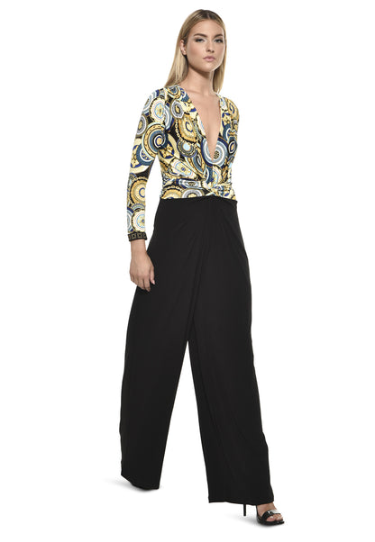 Model wearing Julian Chang Amber Jumpsuit in Contrast/Versus print, featuring a plunging V-neckline, long sleeves, and black draped pants